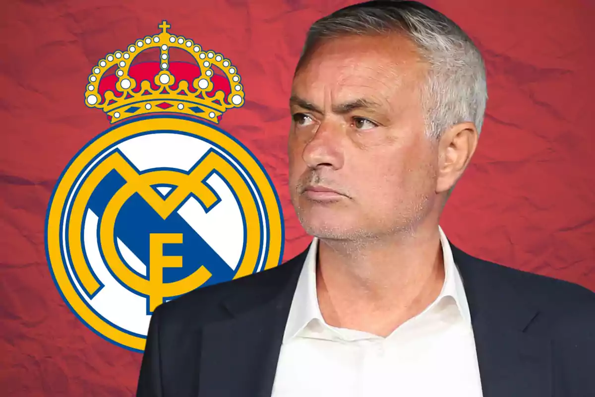 Hombre de cabello canoso con traje oscuro y camisa blanca posando frente al escudo del Real Madrid sobre un fondo rojo