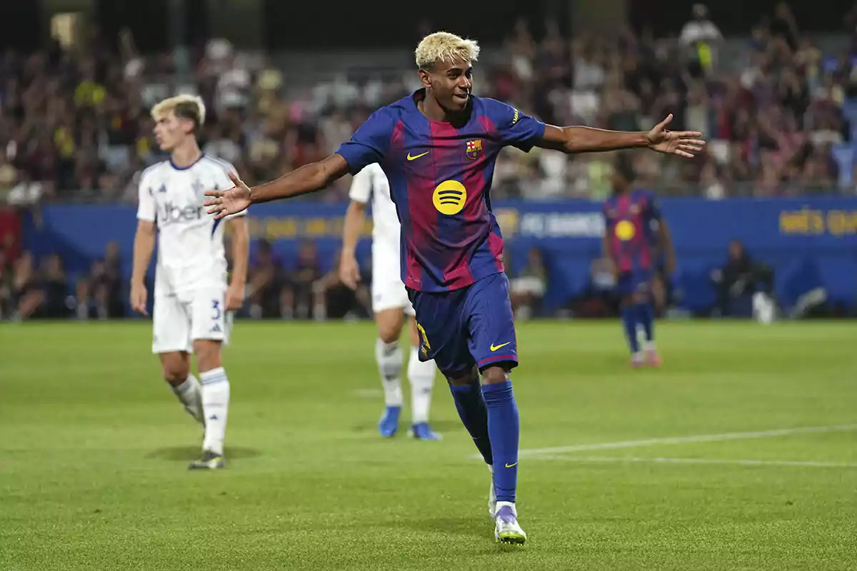 Jugador del Barcelona celebrando un gol con los brazos extendidos durante un partido de fútbol mientras otros jugadores y el público se ven al fondo Jugador del Barcelona celebrando un gol con los brazos extendidos durante un partido de fútbol mientras otros jugadores y el público se ven al fondo