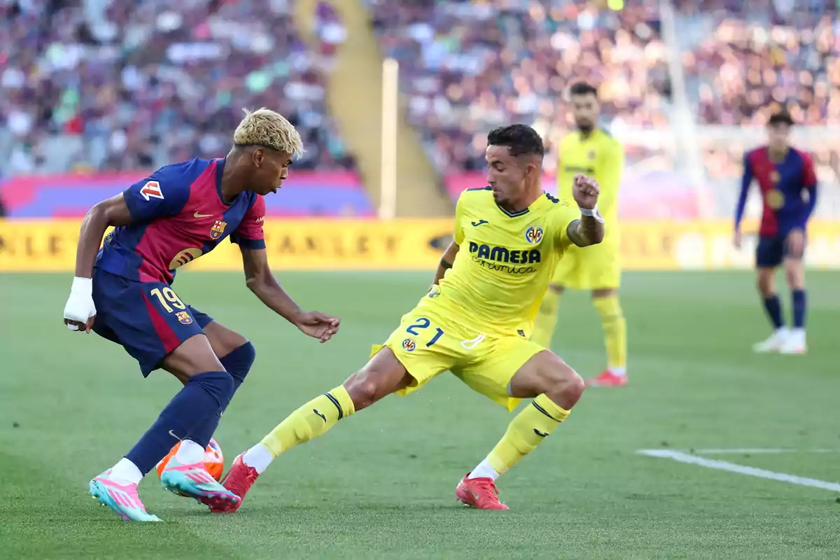 Two players compete for the ball during a match between Barcelona and Villarreal in a stadium full of spectators. Two players compete for the ball during a match between Barcelona and Villarreal in a stadium full of spectators.