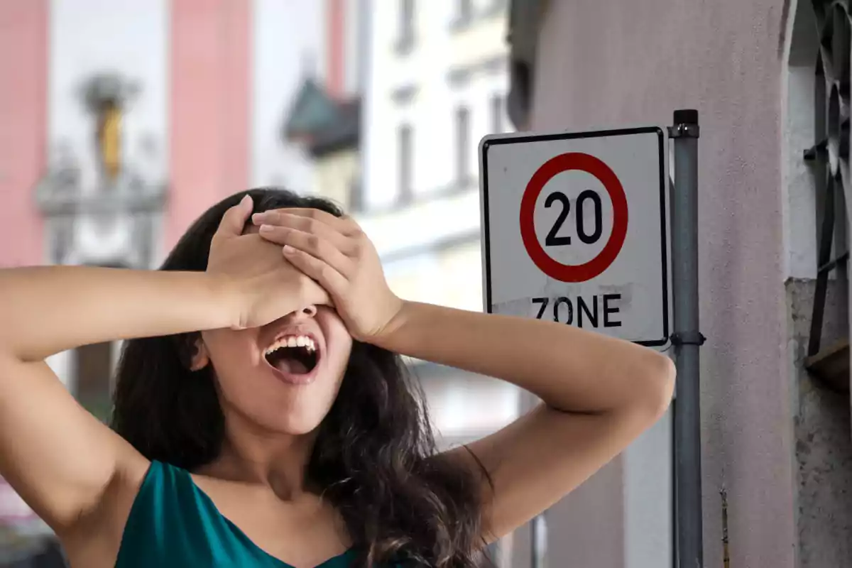 Woman in a blue dress covering her eyes with her hands and a 20 speed limit sign in the background