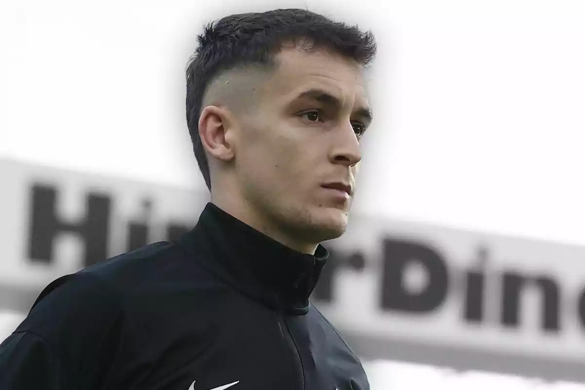 Joven con chaqueta deportiva negra mirando hacia el frente con expresión seria