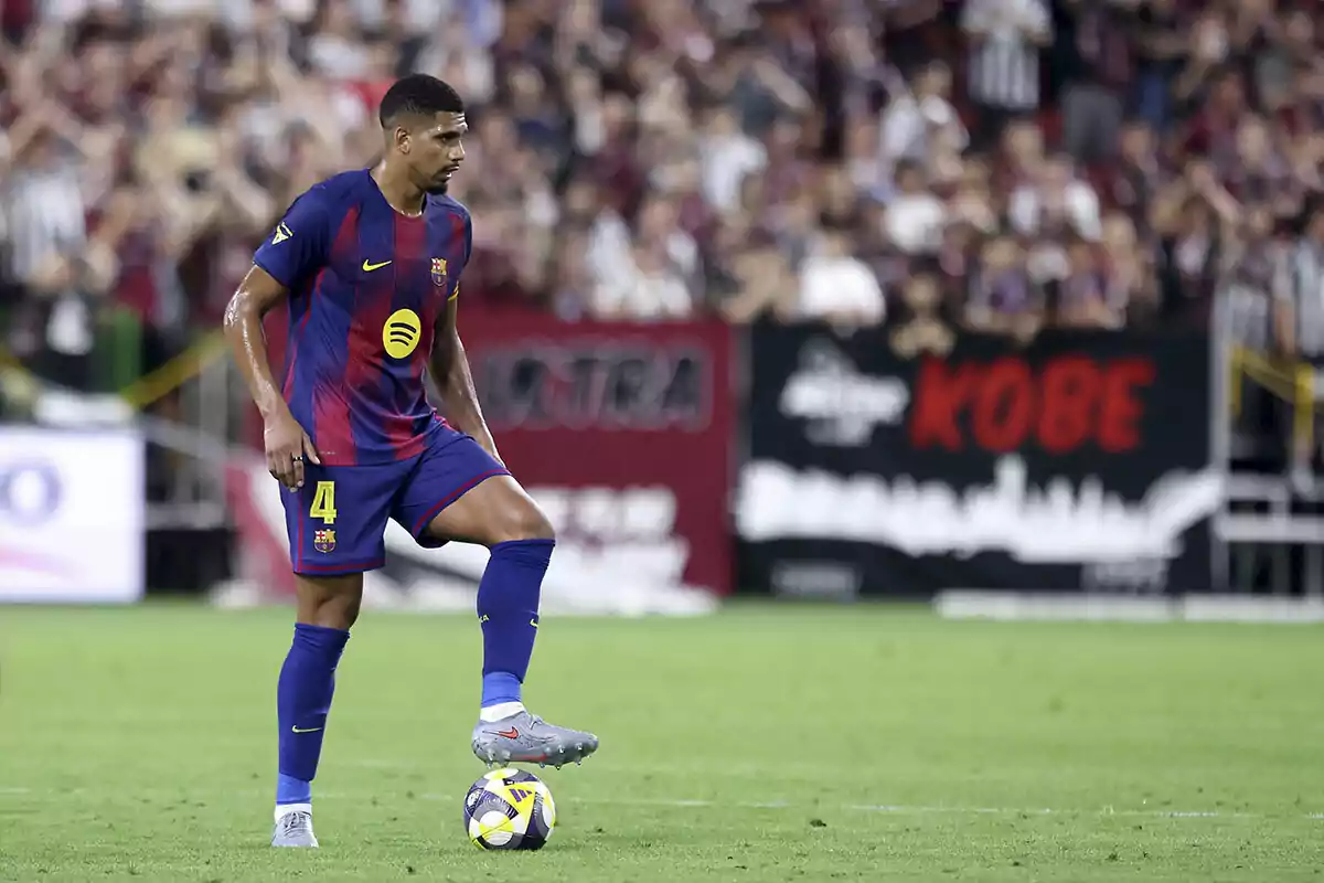 Futbolista del Barcelona con el uniforme azul y rojo controlando el balón en un partido frente a una multitud en el estadio Futbolista del Barcelona con el uniforme azul y rojo controlando el balón en un partido frente a una multitud en el estadio