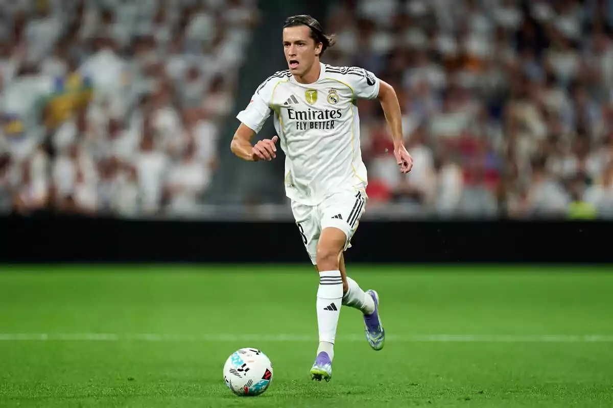 Futbolista del Real Madrid corriendo en el campo durante un partido con el balón cerca de sus pies y el público de fondo. Futbolista del Real Madrid corriendo en el campo durante un partido con el balón cerca de sus pies y el público de fondo.