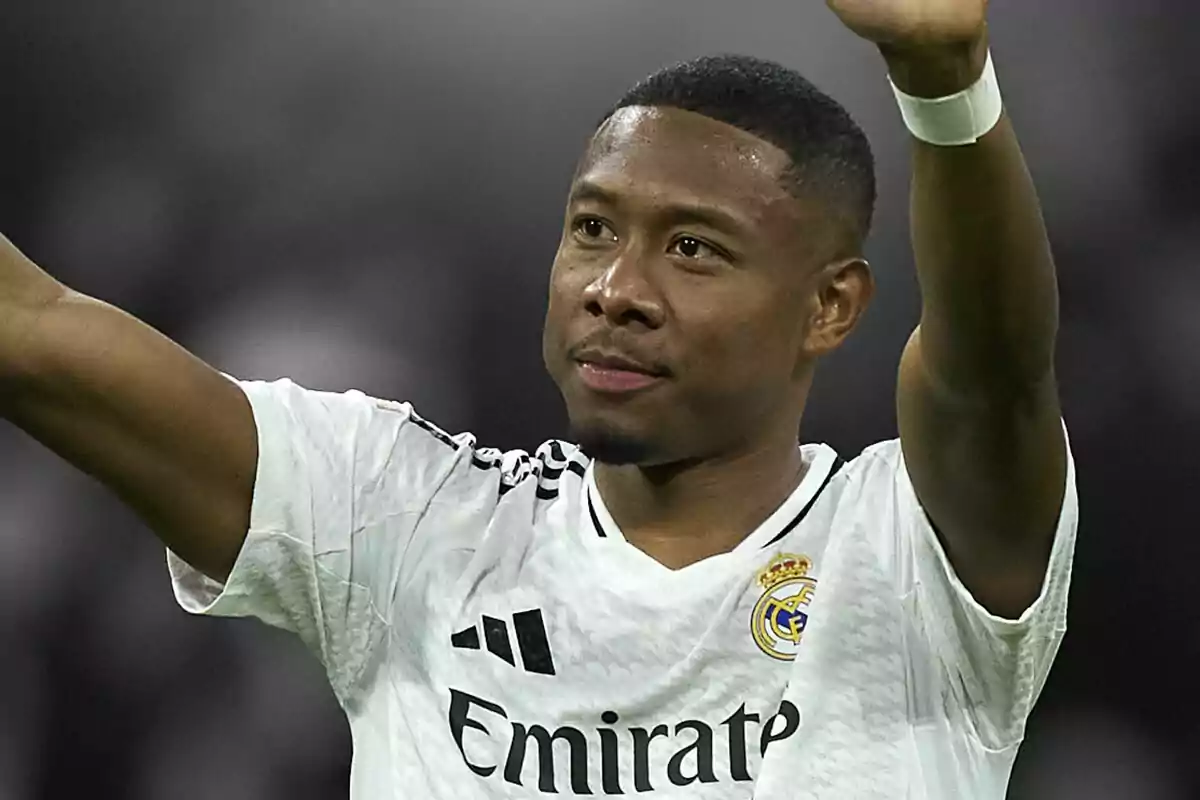 Soccer player wearing a white Real Madrid jersey raising his arms in greeting