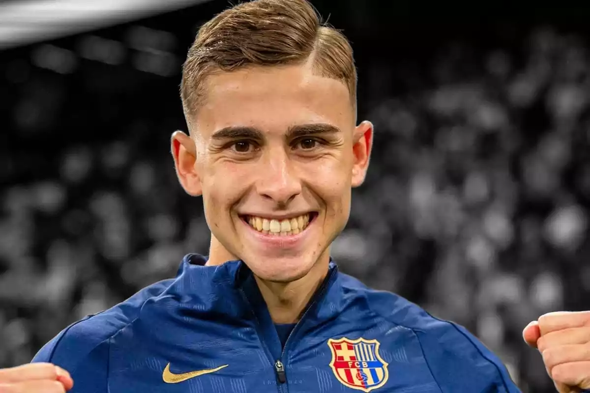 Joven sonriente con chaqueta azul del FC Barcelona celebrando con los puños cerrados