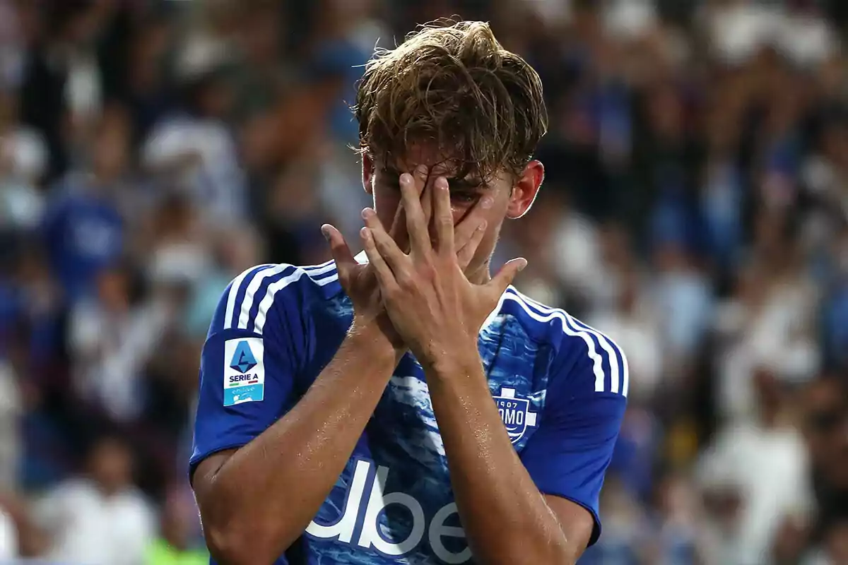 Jugador de fútbol con uniforme azul cubriéndose el rostro con las manos en señal de frustración durante un partido Jugador de fútbol con uniforme azul cubriéndose el rostro con las manos en señal de frustración durante un partido