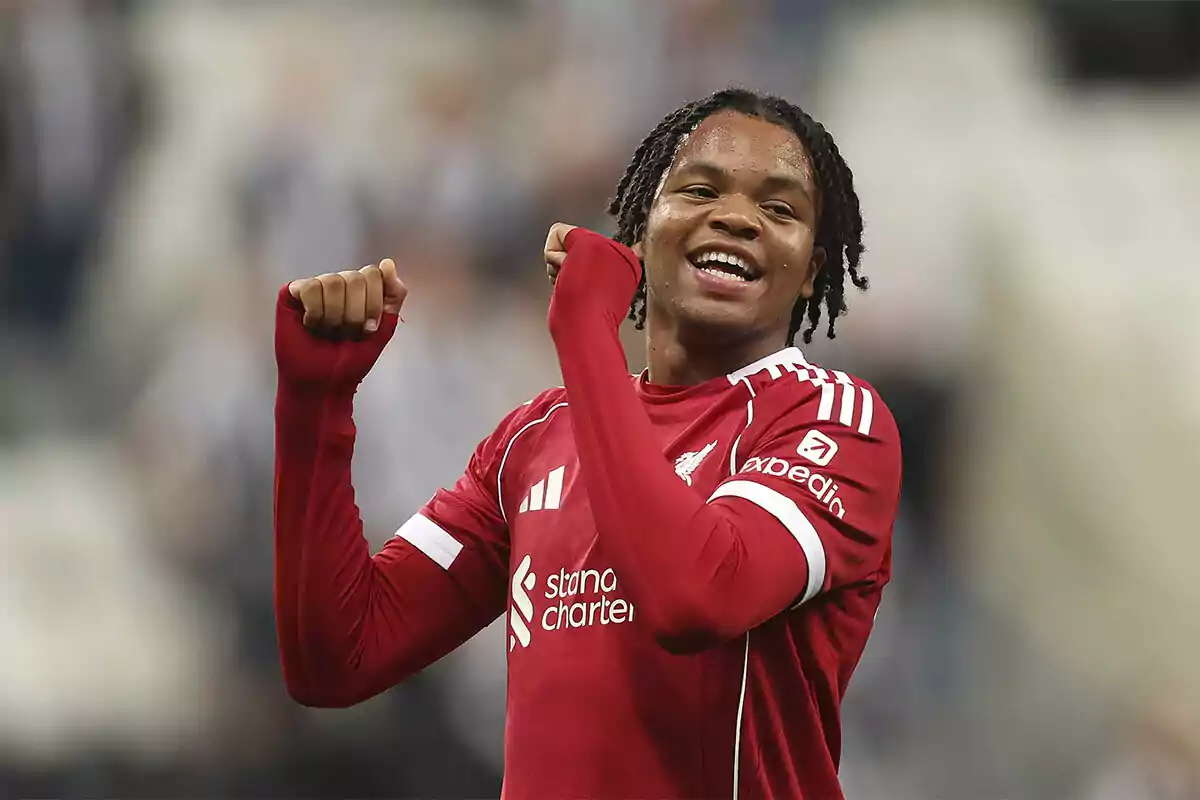 Soccer player in a red uniform celebrating on the field with a big smile