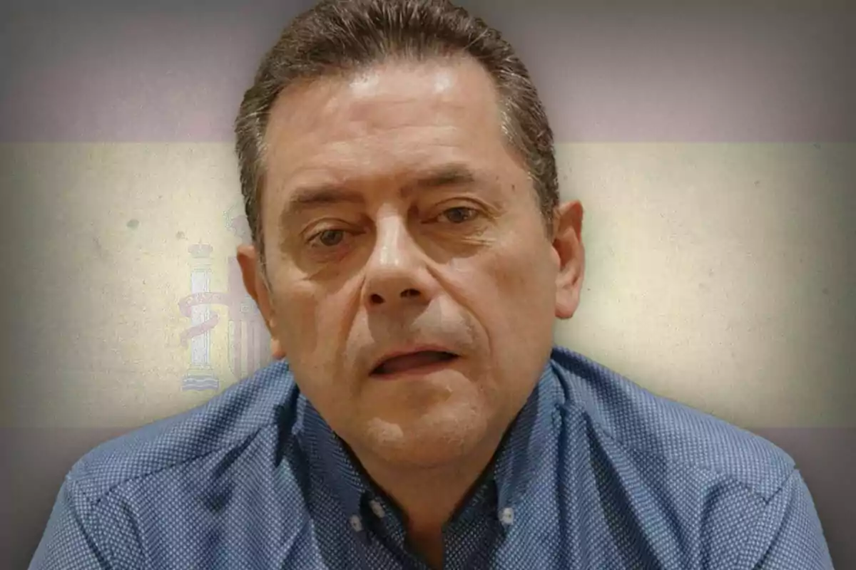 Middle-aged man in a blue jersey in front of a blurred Spanish flag