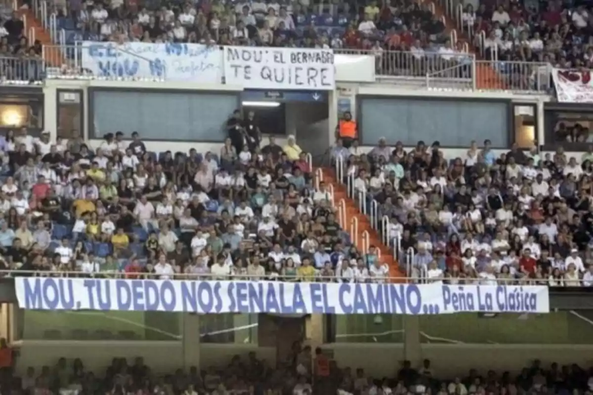 A crowd of people in a stadium with supportive banners.