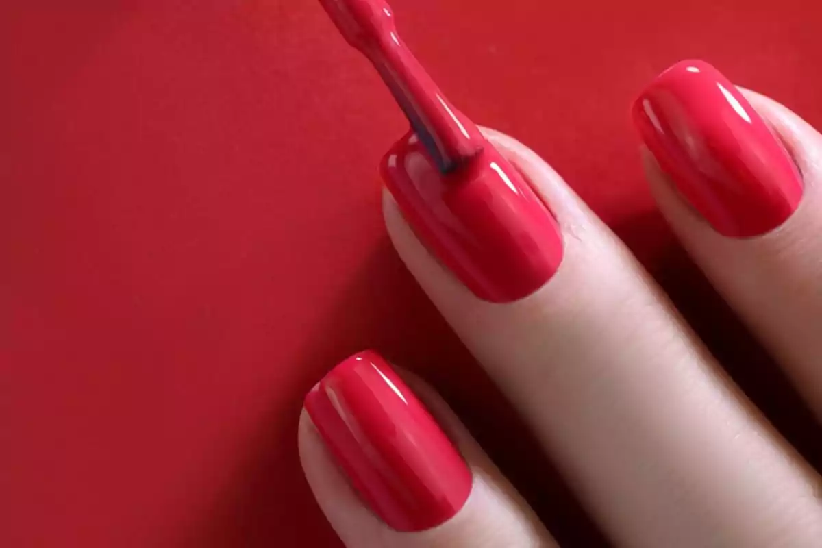 Hand with red nail polish on a red background
