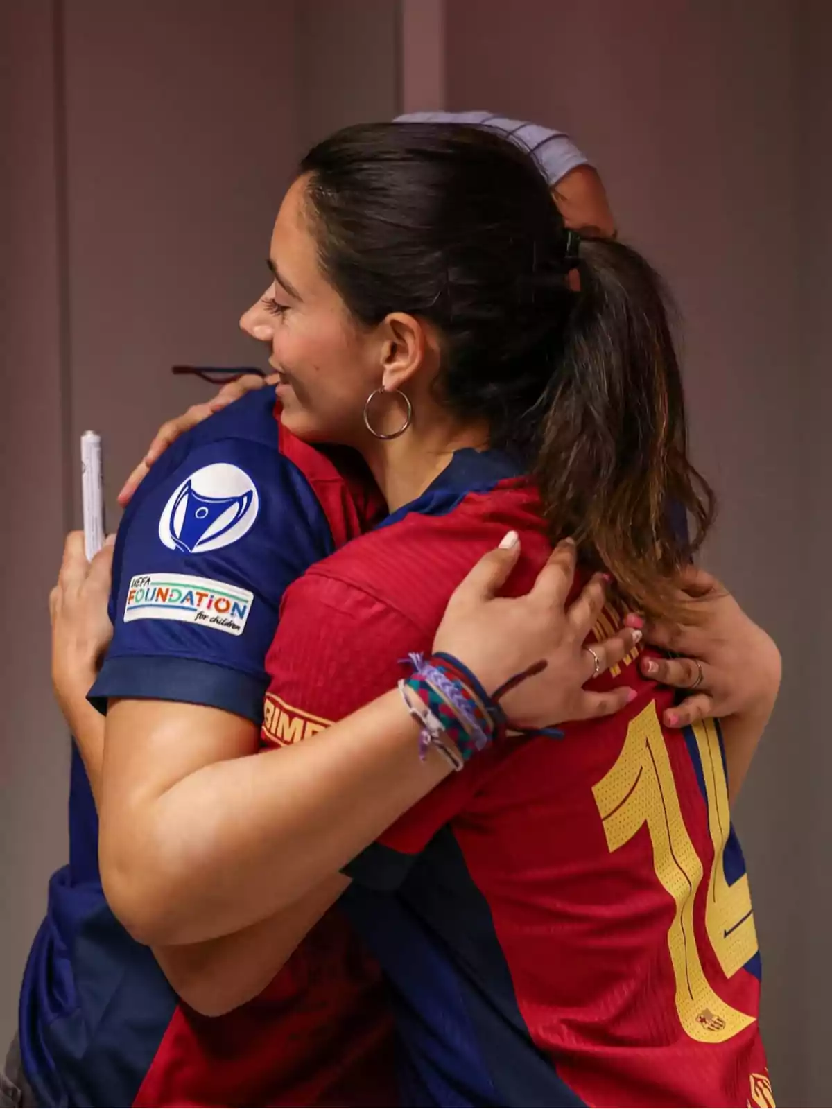 Dos personas con camisetas deportivas se abrazan con afecto.