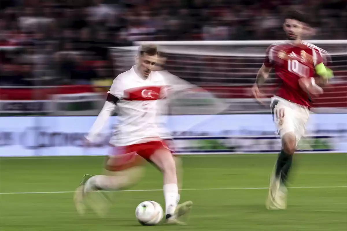 Two soccer players moving during a match, one of them is about to kick the ball.