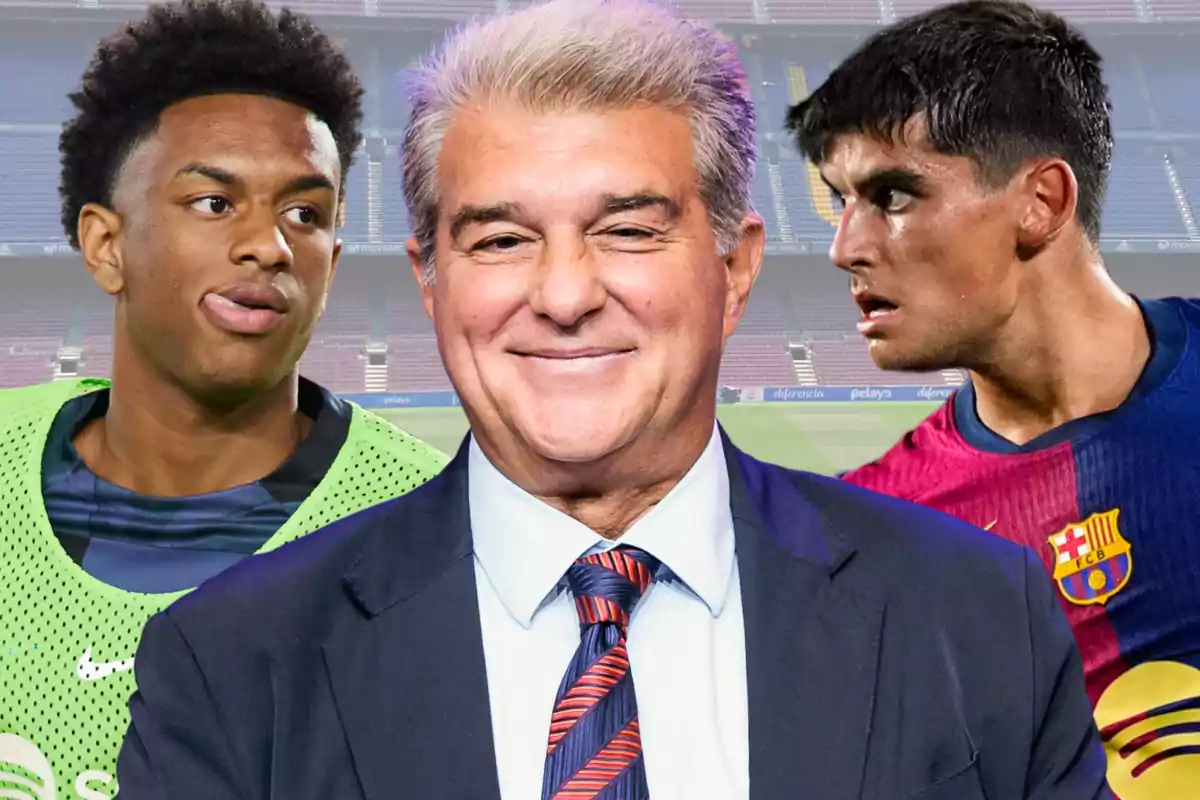 A man in a suit smiles as two soccer players stand beside him in a stadium.