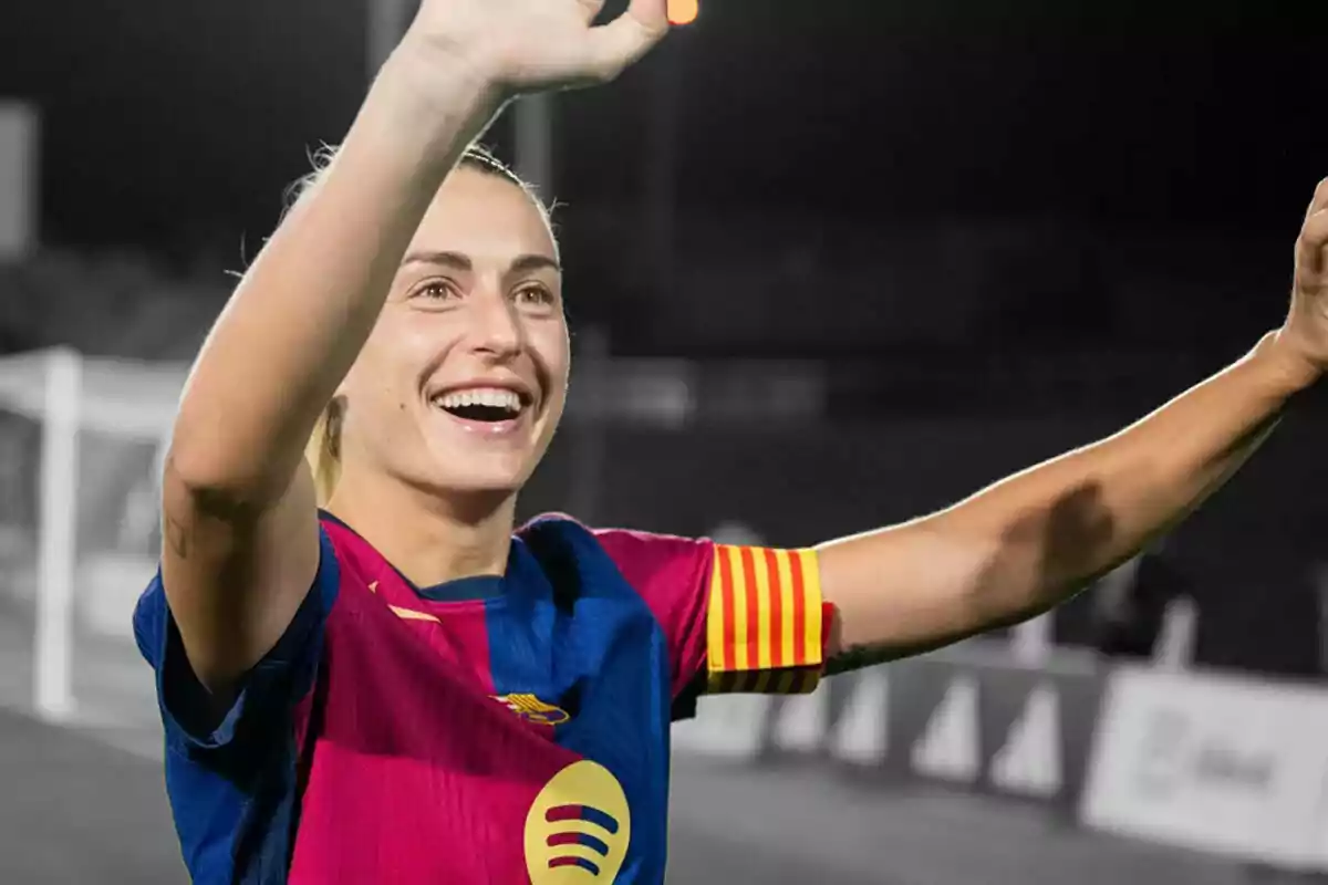 Alexia Putellas sonríe y levanta los brazos en celebración mientras viste el uniforme del FC Barcelona.