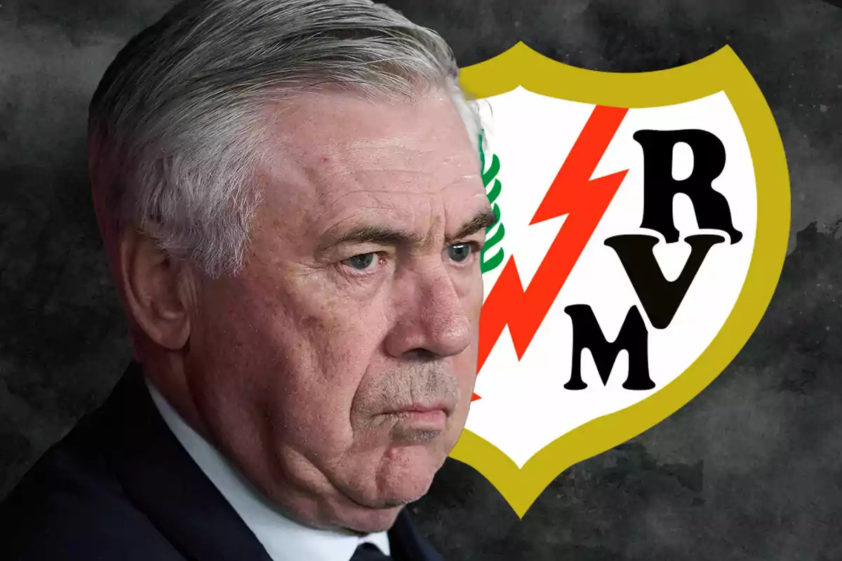 Carlo Ancelotti with a serious expression in front of Rayo Vallecano's shield.