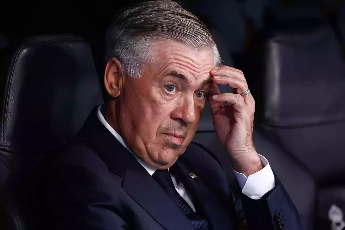 Carlo Ancelotti scratches his forehead while sitting on the Santiago Bernabéu bench