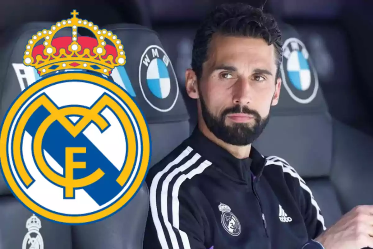 A man in a Real Madrid uniform sitting on a bench with the club's logo in the foreground.