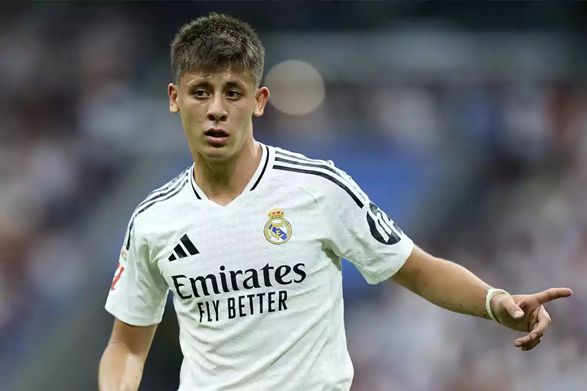 Jugador de fútbol con uniforme blanco del Real Madrid en el campo.