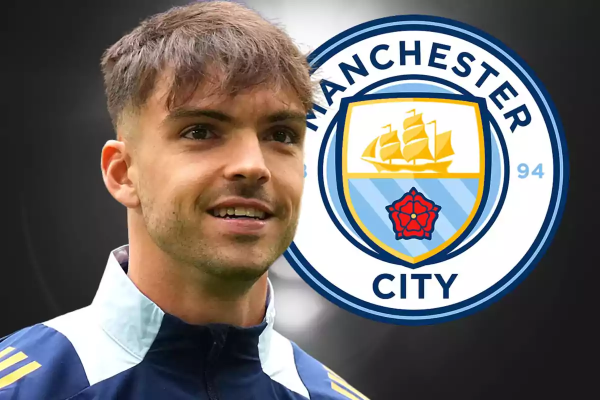 A man in a sports jacket in front of the Manchester City logo.