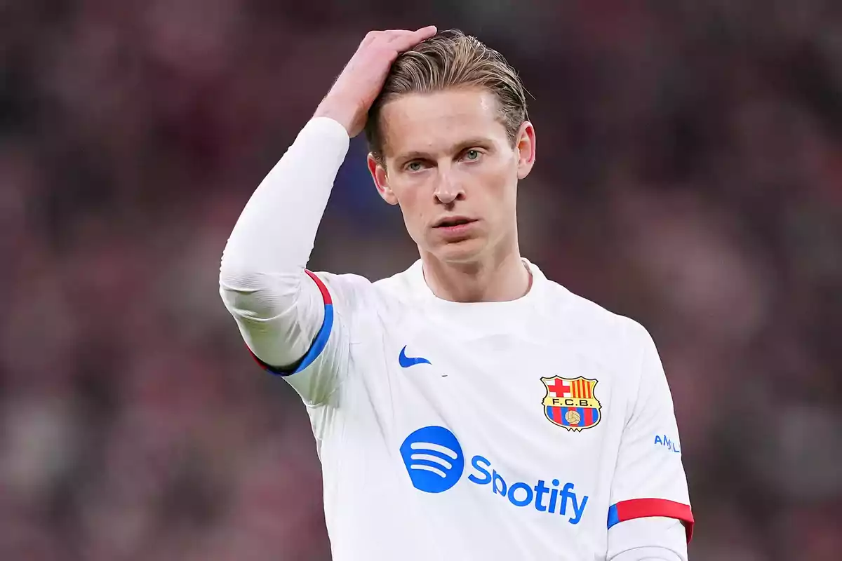 soccer player in white FC Barcelona uniform touching his head during a match.