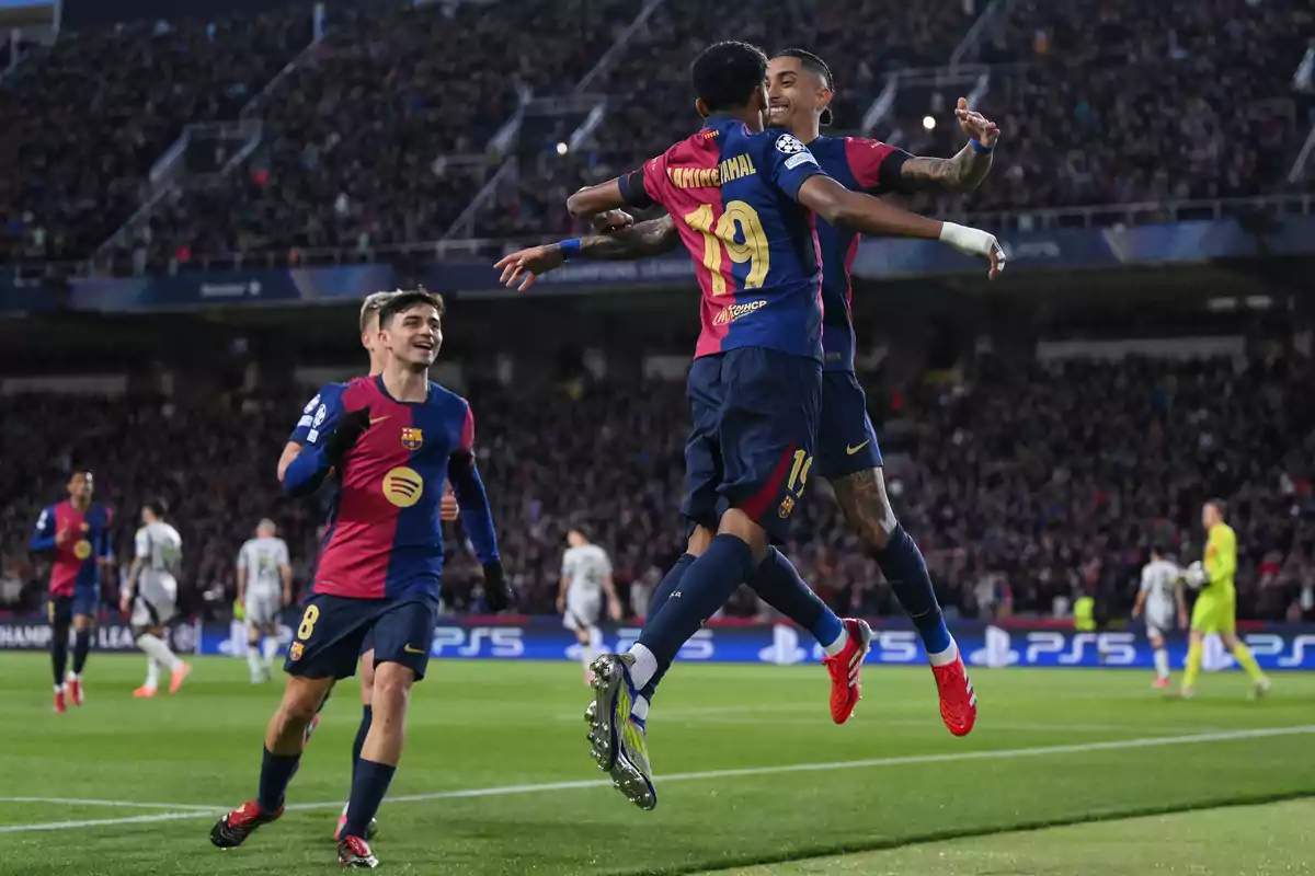 Jugadores de fútbol del Barcelona celebran un gol en un estadio lleno de espectadores.