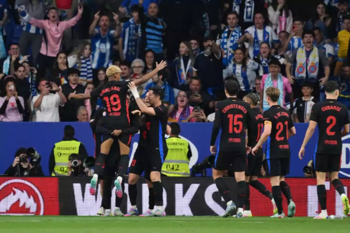 Soccer players celebrate a goal in front of a crowd of fans in a stadium. Soccer players celebrate a goal in front of a crowd of fans in a stadium.