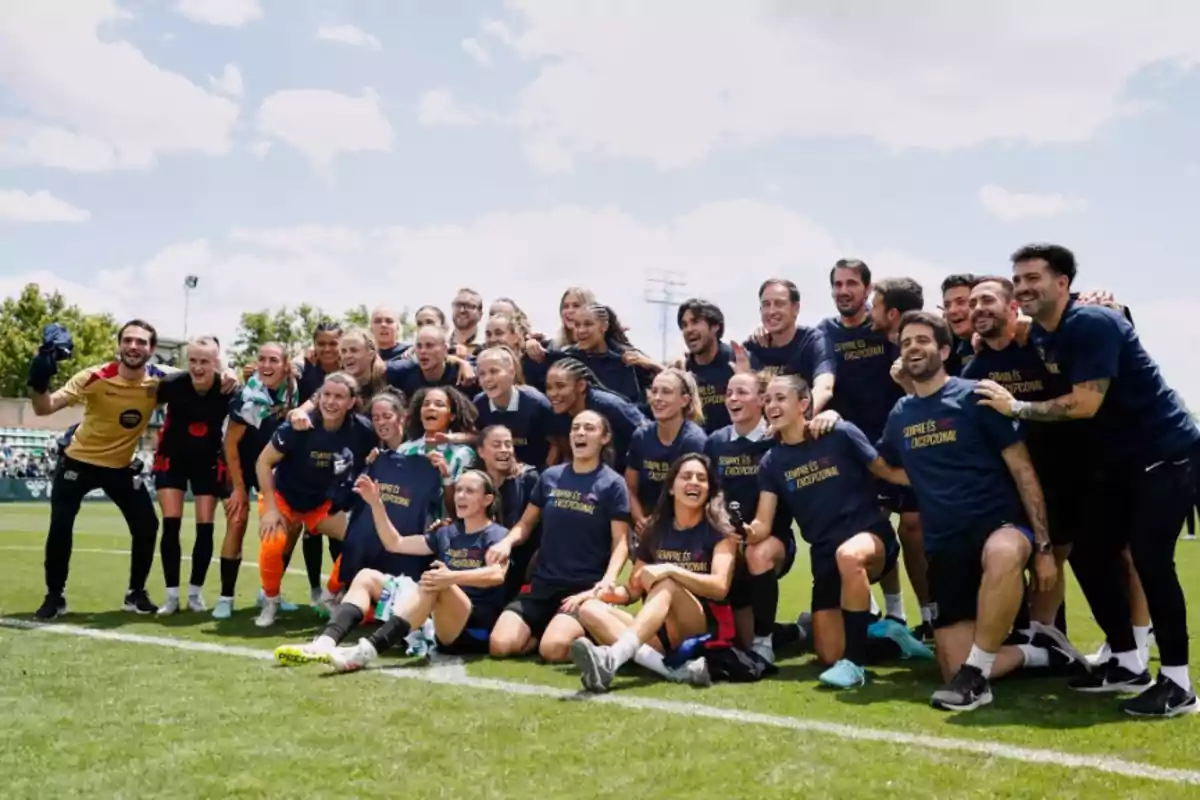 Un grupo de personas sonríe y posa para una foto en un campo de fútbol, algunas llevan camisetas que dicen Un grupo de personas sonríe y posa para una foto en un campo de fútbol, algunas llevan camisetas que dicen