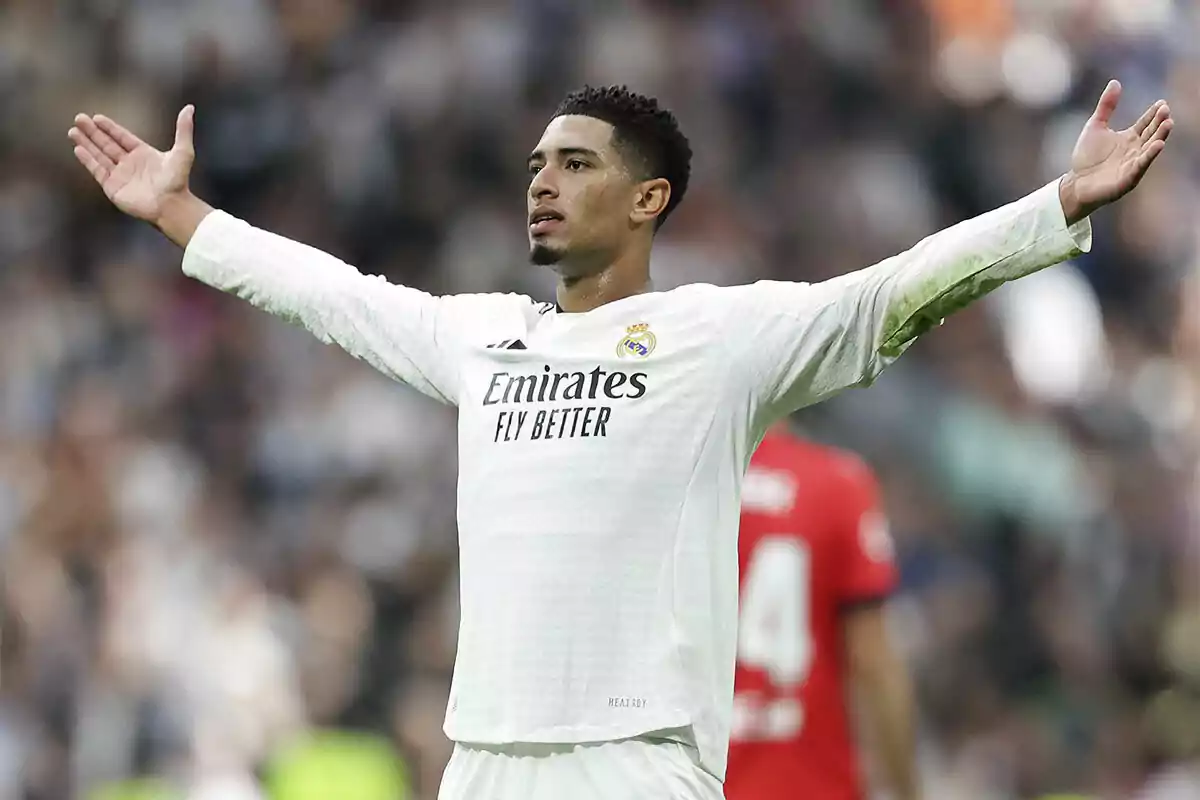 Football player with arms outstretched wearing Real Madrid uniform in a stadium.