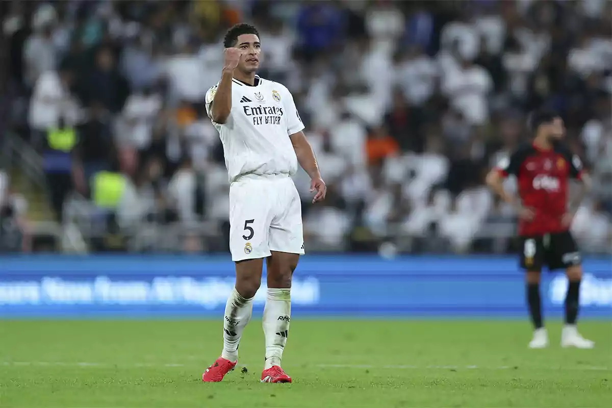 A Real Madrid soccer player celebrating on the field with his fist raised during a match. A Real Madrid soccer player celebrating on the field with his fist raised during a match.