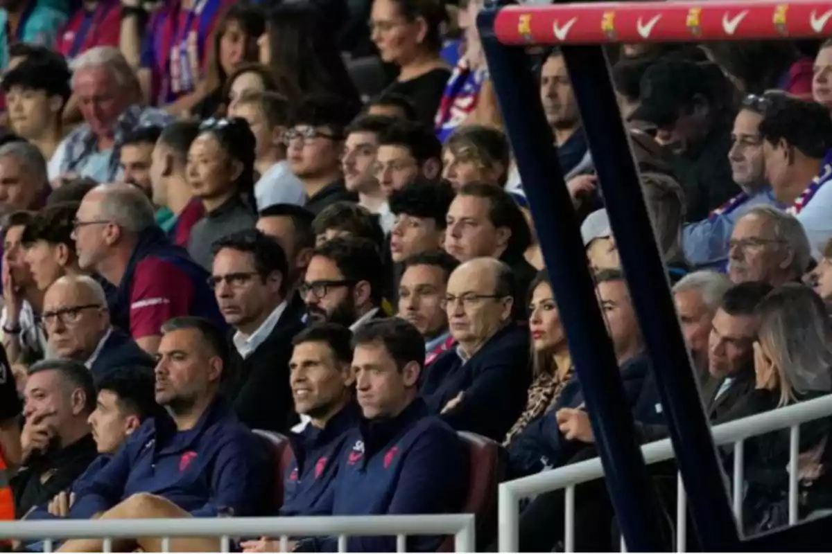 A group of people attentively watch a sporting event from the stands of a stadium.