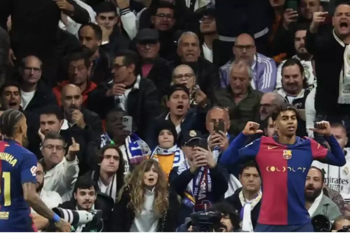 A soccer player celebrates in front of a crowd of fans in the stands, some of whom are making disapproving gestures.