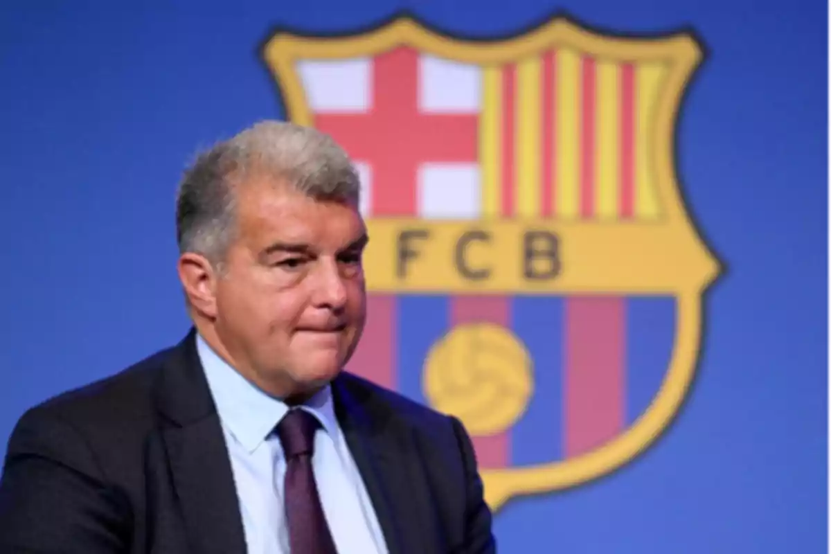 Man in suit in front of the FC Barcelona crest.