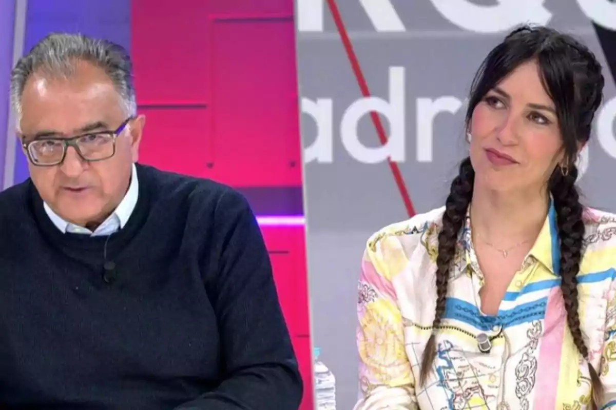 Two people on a TV set with a colorful background, one of them is wearing glasses and a dark sweater, the other has braided hair and is wearing a patterned jersey. Two people on a TV set with a colorful background, one of them is wearing glasses and a dark sweater, the other has braided hair and is wearing a patterned jersey.