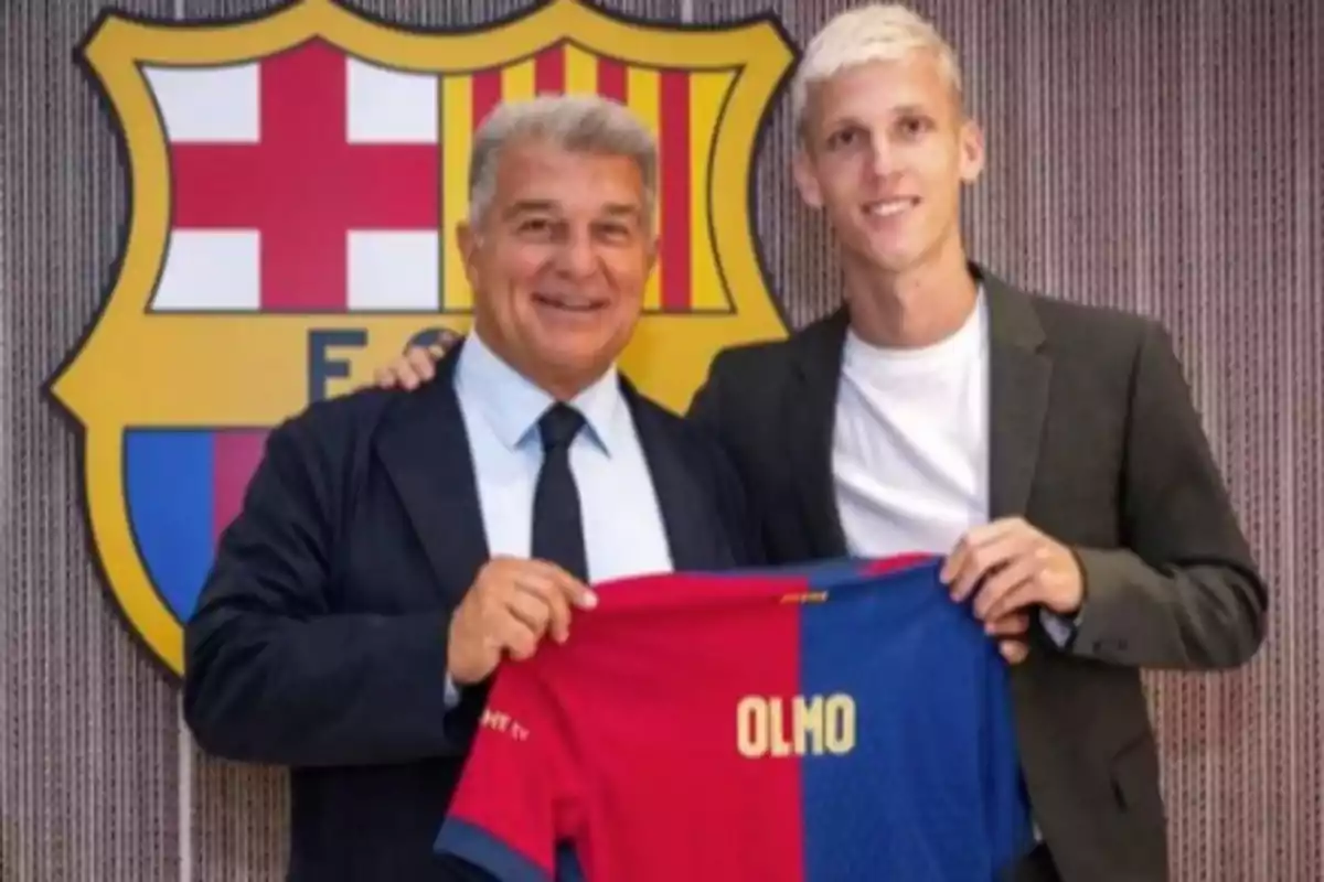 Two people pose in front of the FC Barcelona crest holding a team jersey with the name Two people pose in front of the FC Barcelona crest holding a team jersey with the name
