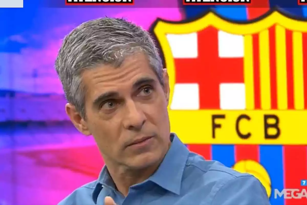 A man with grey hair and a blue jersey is on a television program with the FC Barcelona crest in the background.