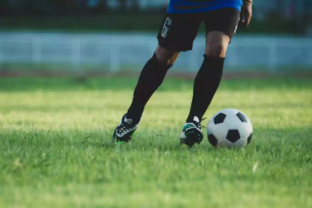 Person playing soccer on a grass field.