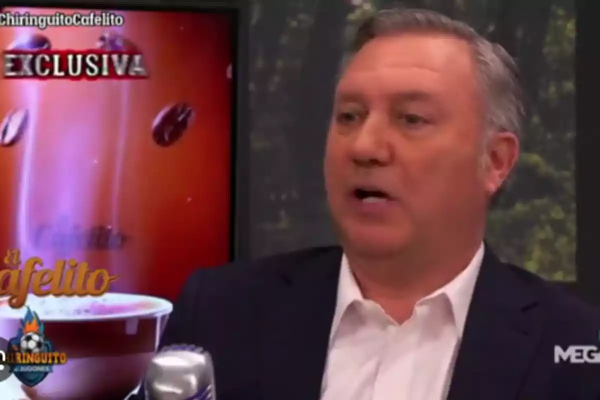 A man speaking on a television show with a background showing a coffee cup and the word "Exclusive."