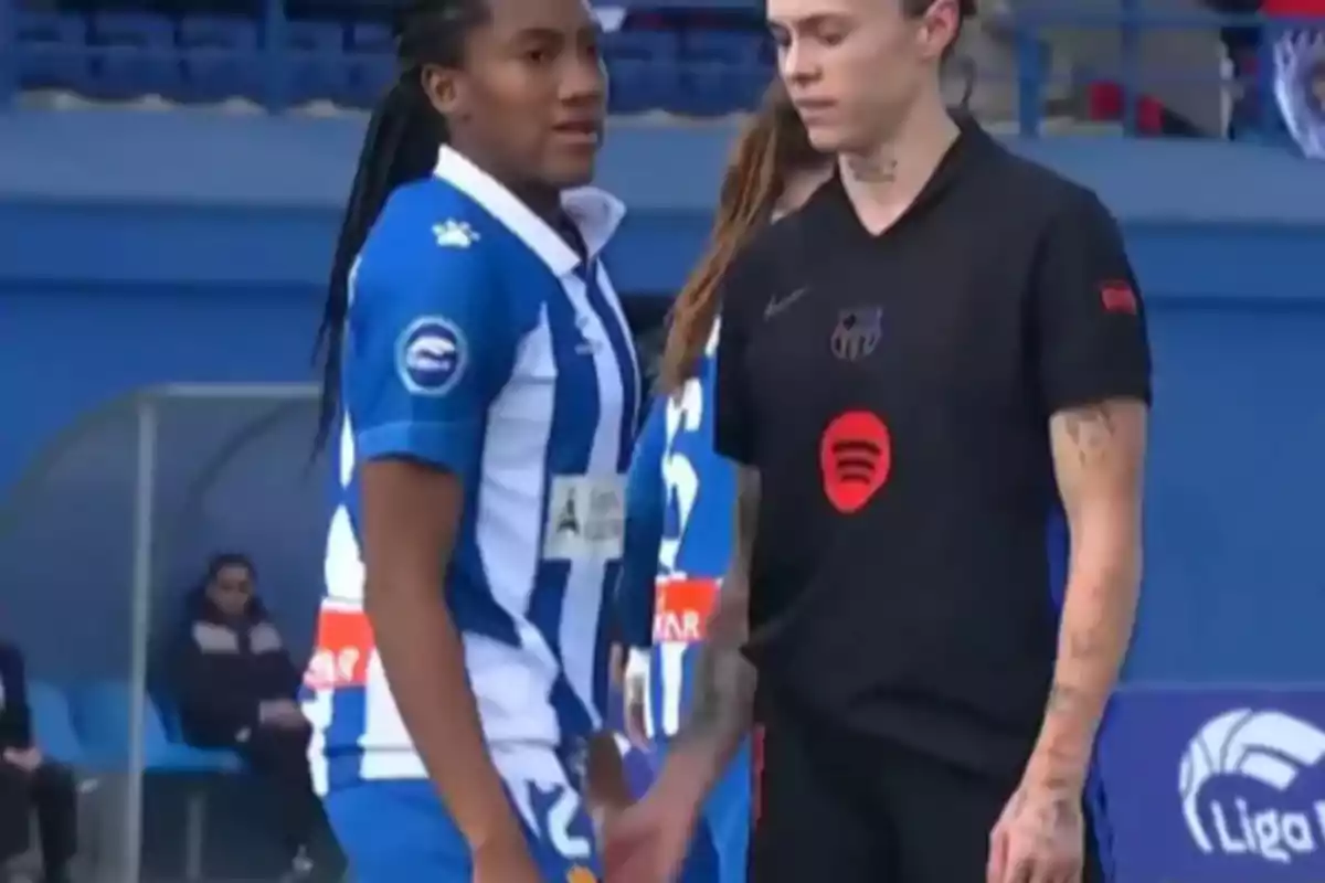 Two players on the field, one in a blue and white uniform and the other in a black uniform, during a match.