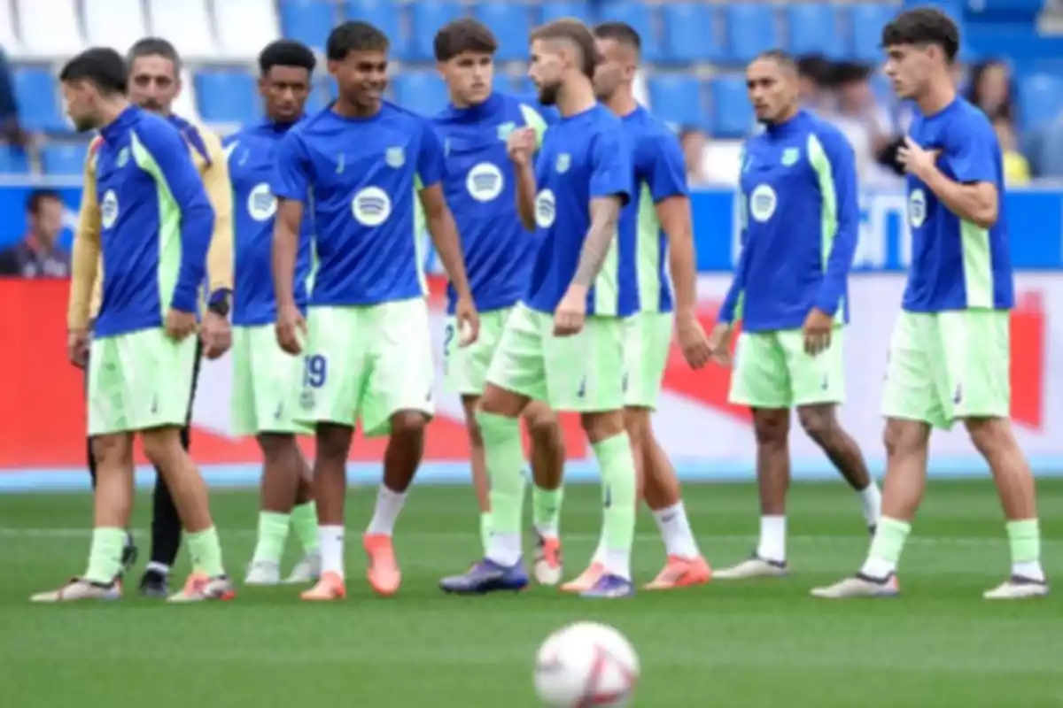 A group of players in blue and green uniforms is on the field during a training session.