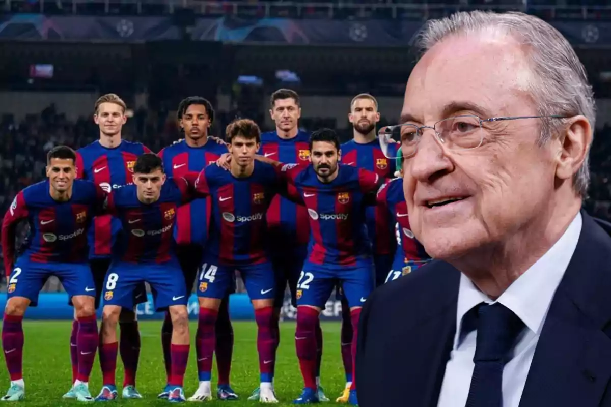 Un grupo de jugadores de fútbol con uniforme azul y rojo posando en el campo con un hombre mayor en traje en primer plano.