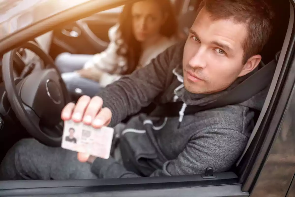 Hombre sentado en el asiento del conductor de un auto mostrando una identificación mientras una mujer está sentada en el asiento del copiloto