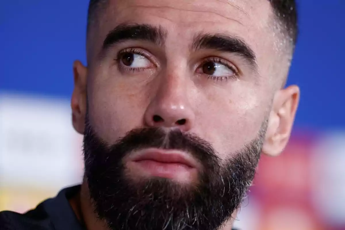 Close-up of a man with a beard and short hair looking to the side.