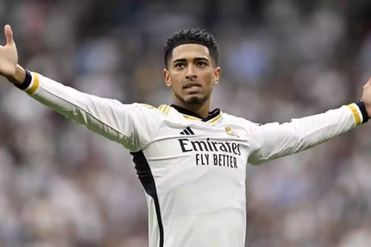 A soccer player with his arms outstretched, wearing the white uniform of Real Madrid.