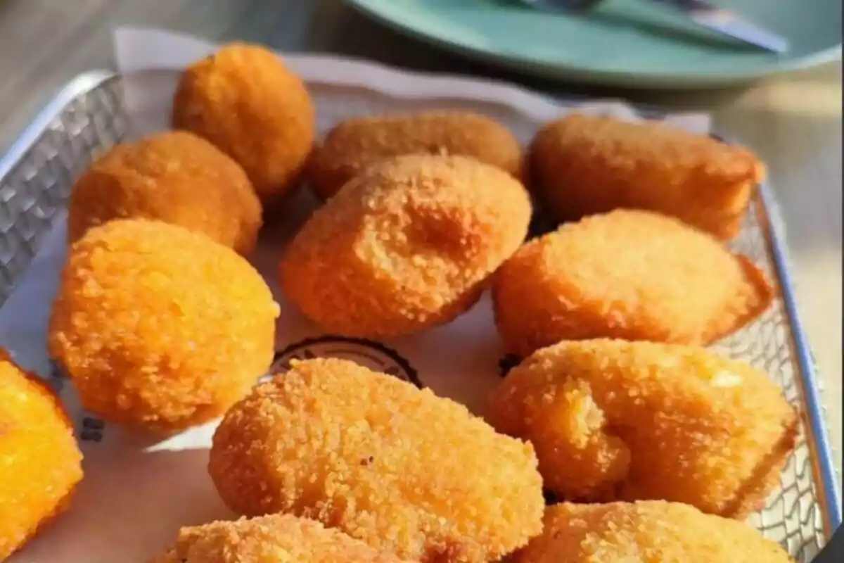 Una bandeja de croquetas doradas y crujientes sobre papel encerado.