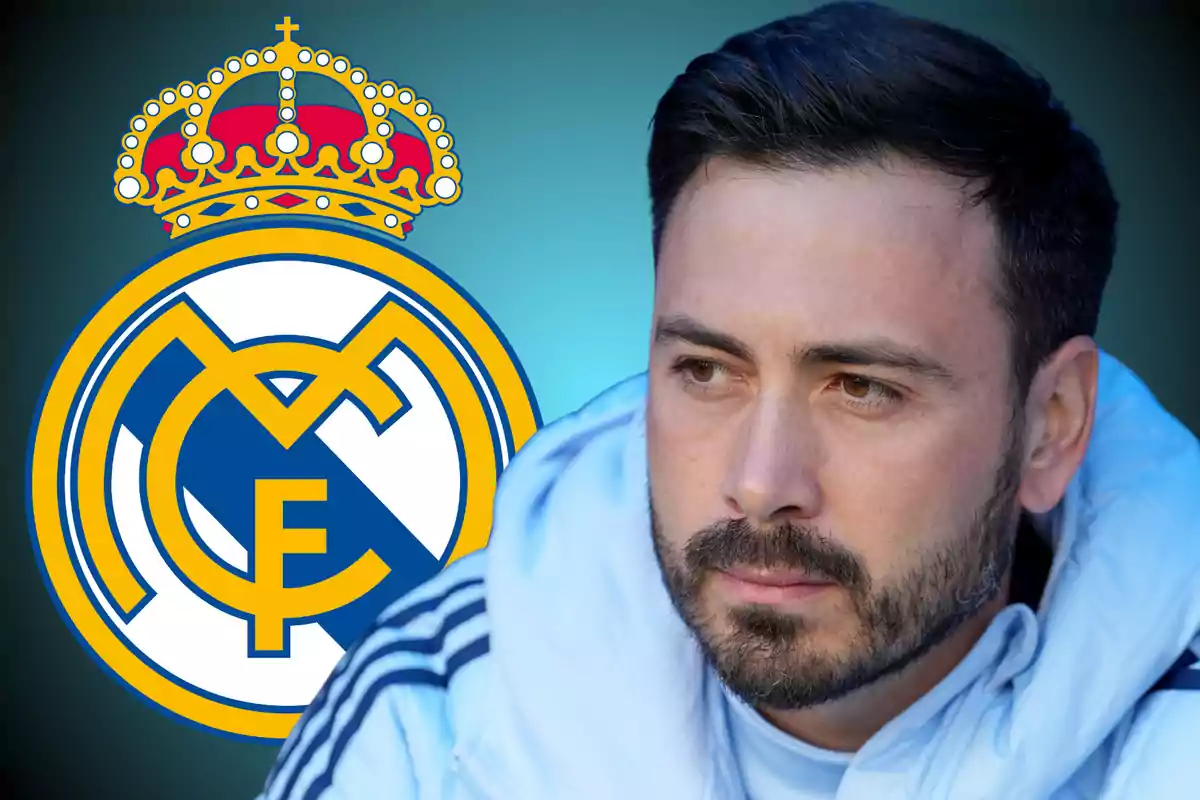 Hombre con barba y chaqueta blanca sentado frente al escudo del Real Madrid sobre un fondo azul