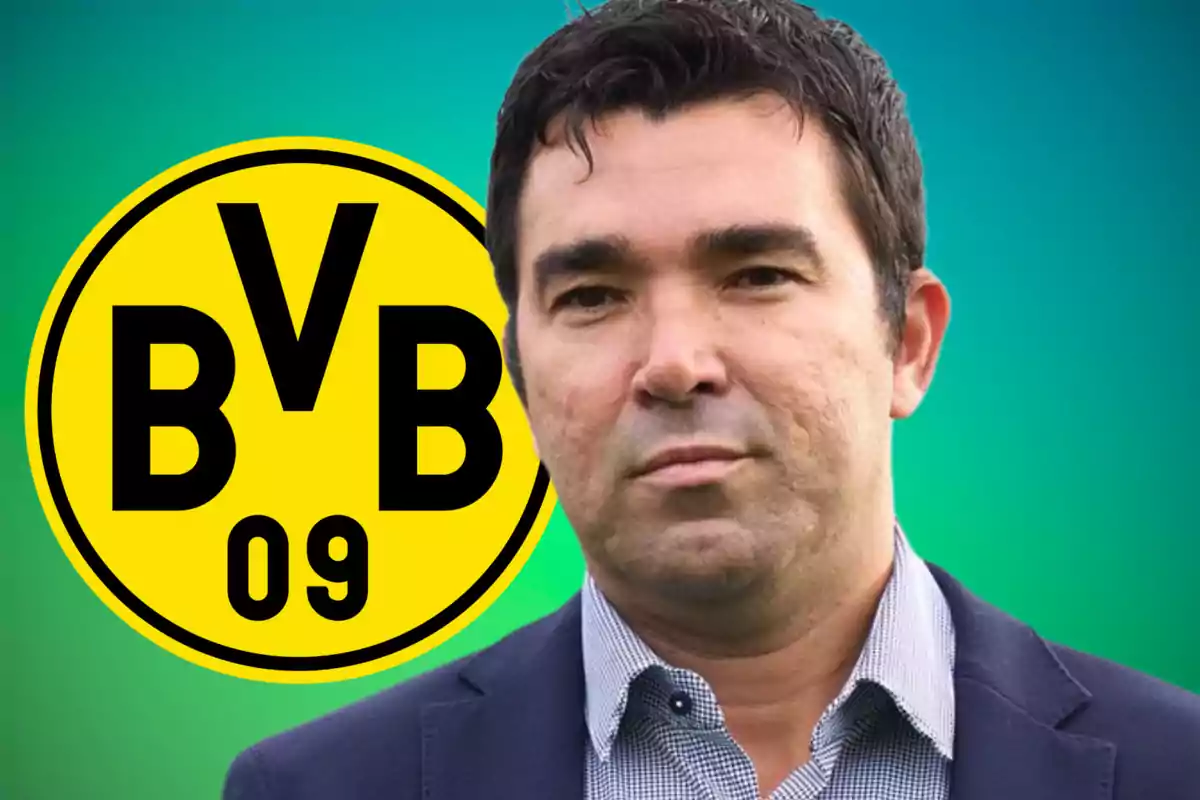 Un hombre con traje frente al logo del Borussia Dortmund sobre un fondo verde.