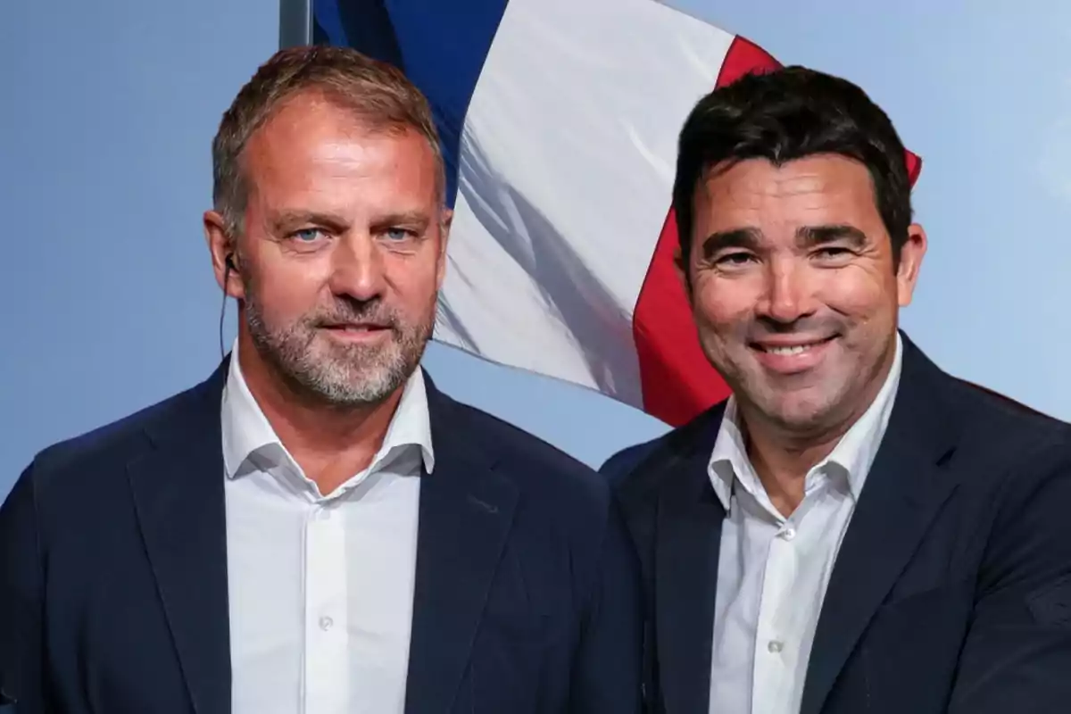 Dos hombres con trajes oscuros y camisas blancas posan frente a una bandera de Francia.