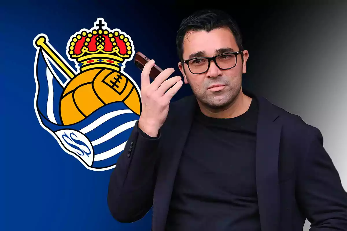 Un hombre con gafas sostiene un teléfono móvil frente a un logotipo de un equipo de fútbol con un balón y una corona.