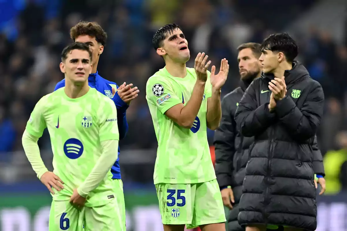 Jugadores de fútbol con uniforme verde y azul aplauden en el campo después de un partido. Jugadores de fútbol con uniforme verde y azul aplauden en el campo después de un partido.