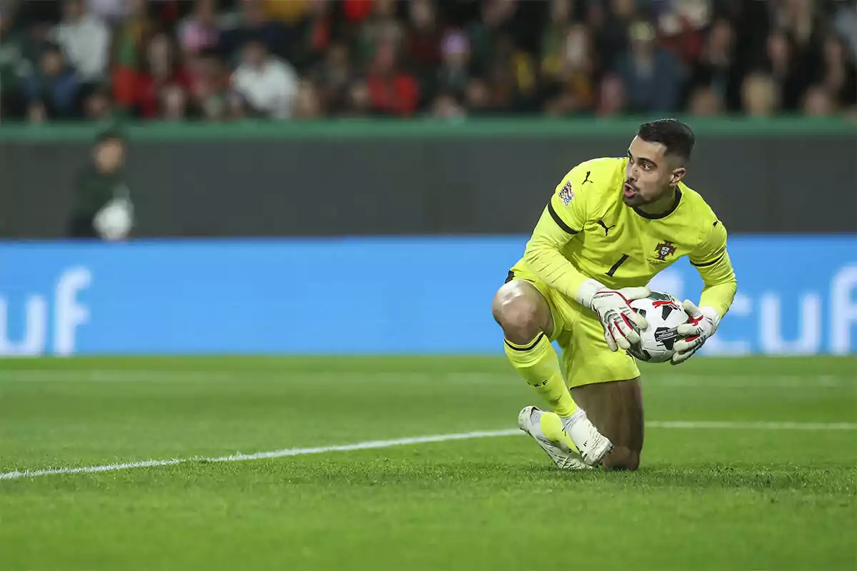 Soccer goalkeeper in a yellow uniform stopping the ball during a match